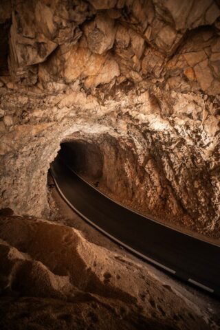 A dark road curves through a rocky cave tunnel.